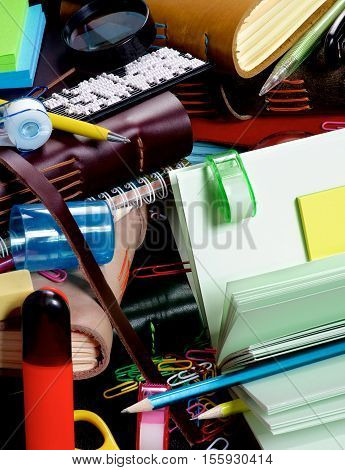 Background of Stationery Items with Notepads Pens Pencils Paper Clips Tape Dispenser Sharpener Stickers Loop and Markers closeup