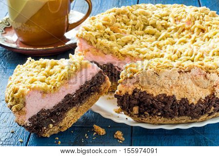 Homemade festive multilayer cake with jam chocolate marshmallows streusel and a cup of tea on a blue wooden background. Selective focus