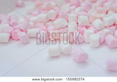 Colorful mini marshmallows background close-up texture. A pile of different mini white pink and orange puffy marshmallows. Marshmallow concept. Wallpaper for desktop. Selective focus.