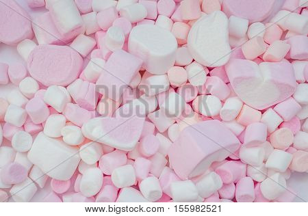 Colorful marshmallows background close-up texture. A pile of different mini white pink and orange in form of heart puffy marshmallows. Marshmallow concept. Wallpaper for desktop. Top view.