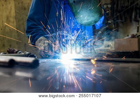 Welder in his workshop welding metal, lots of sparks flying around