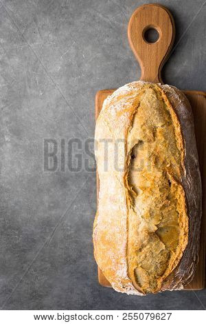 Freshly Baked Hand Crafted Rustic Bread Loaf On Cutting Board Dark Stone Background. Authentic Rusti