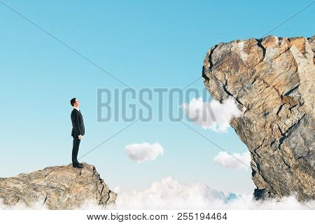 Side View Of Young Businessman On Small Cliff Thinking How To Get Onto Big One. Career Development A