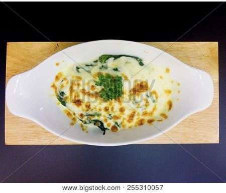 Baked Spinach With Cheese Is Decorated With Parsley Leaves That Is In  White Bowl, On The Wooden Tra