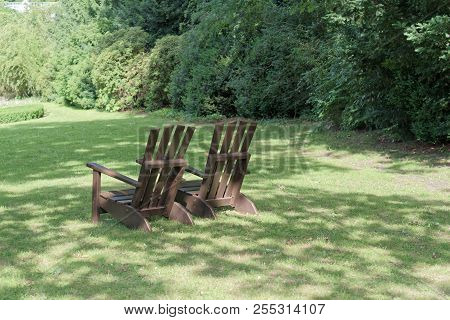 Two Wooden Chairs For Relaxing On The Green Meadow In A Park