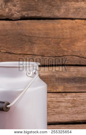 Steel Milk Can. Old Wooden Desk Background.