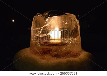 Candle In Frozen Ice Lantern Surrounded With Snow