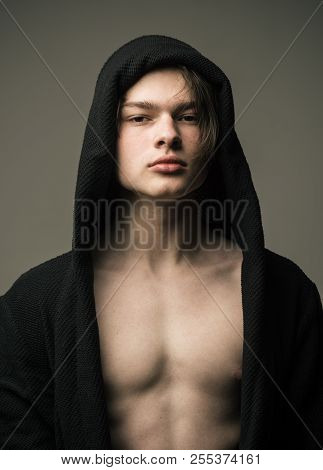 Guy On Confident Face In Black Hood, Grey Background. Masculinity Concept. Macho In Black Bathrobe W