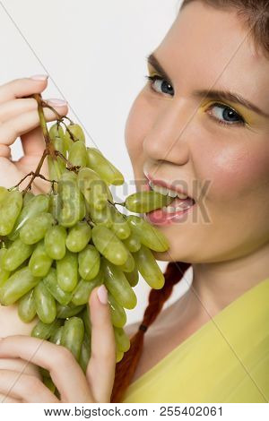 Beautiful Redhead Woman Is Eating Grapes. Concept Of Healthy Eating