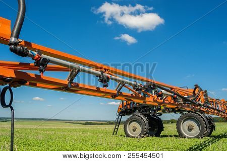 Self-propelled Sprayer Works On A Field Under A Blue Sky With Clouds