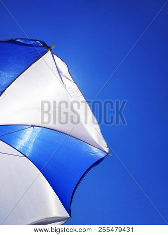 Sun Beach Umbrella Parasol On Sunny Day On Background Of A Blue Sky Giving Shade And Protection.