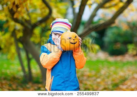Happy Cute Little Kid Boy With Halloween Pumpkin Lantern. Funny Child In Colorful Clothes Having Fun