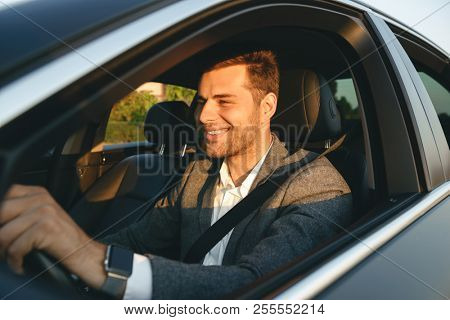 Confient smiling bussinesman in suit driving his car