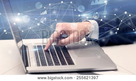 Businessman typing on laptop with linked reports charts grapghs around