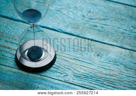 Photo of hourglass on blue wooden background