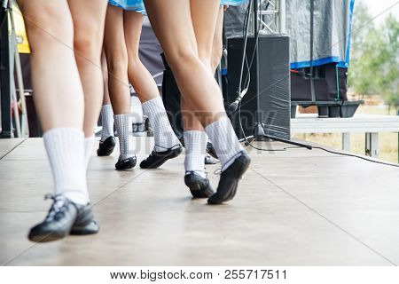 Female Legs Of Four Irish Dancers In Blue Dresses On The Stage Closeup