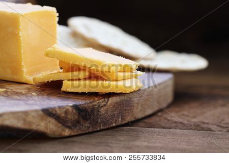 Block Of Cheddar Cheese And Slices Over A Rustic Background.. Extreme Shallow Depth Of Field With Se