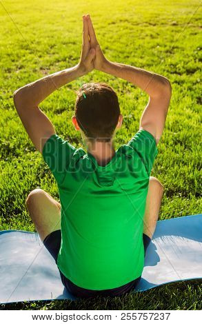 Seated Yoga Pose. Man Practicing Yoga Sitting On Mat In The Park. Healthy Active Lifestyle