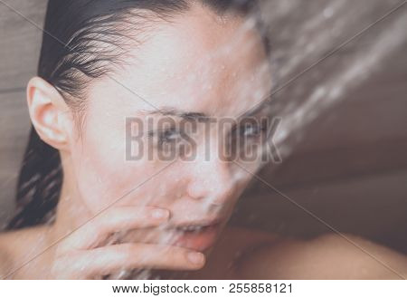 Young beautyful woman under shower in bathroom.