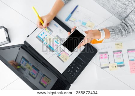 app design, technology and business concept - web designer or developer with smartphone working on user interface and drawing sketches at office