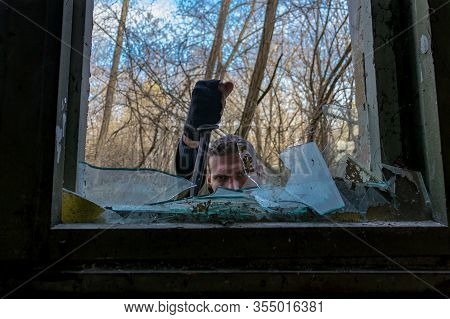 Man With In A Military Outfit With A Stabbed Knife In A Window Frame