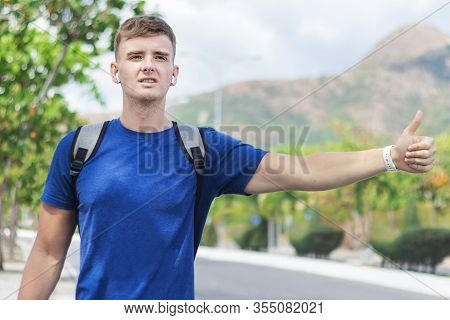 Handsome Guy, Young Man Traveler Trying To Stop, Catch Taxi Car, Cab. Boy Standing Near Road With Ba