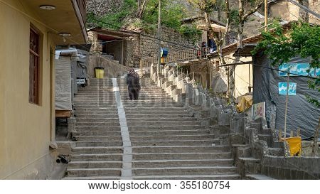 Masuleh, Iran - May 2019: Unidentified Old Iranian Woman Walking In The Roads Of Traditional Masuleh