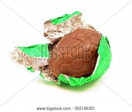 An Isolated Over White Image Of A Hollow Chocolate Egg Being Unwrapped From Its Green Foil.