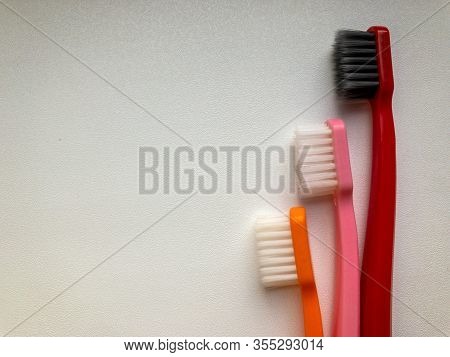 Three Multi-colored Toothbrushes On A White Background