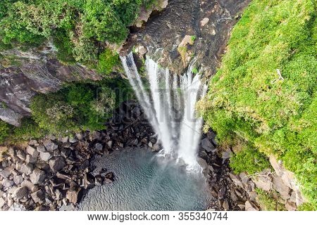 Looking Down Aerial View Of The High Waterfall Jeongbang And Lagoon On Jeju Island, South Korea.