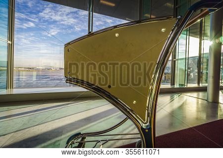 Backlighted Airport Luggage Cart With Large Window Panes In The Background With View On The Tarmac