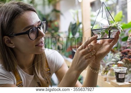Young Woman Gardener In Spectacles Looking At Cuttings Of Tradescantia In A Small Glass Florarium Fo
