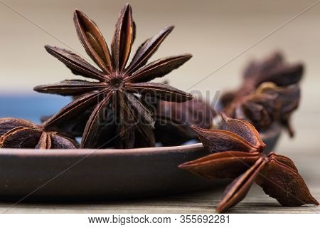 Star Anise With And Without Seeds, In A Clay Dish On A Light Wooden Surface. Spice For The Recipe. B