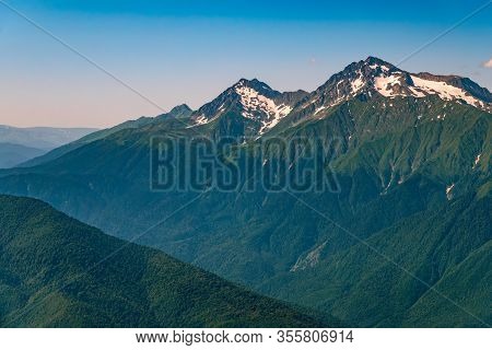 High Mountains With Green Slopes And Snowy Peaks. Mountain Ranges In Summer. Mount Chugush, Height 3