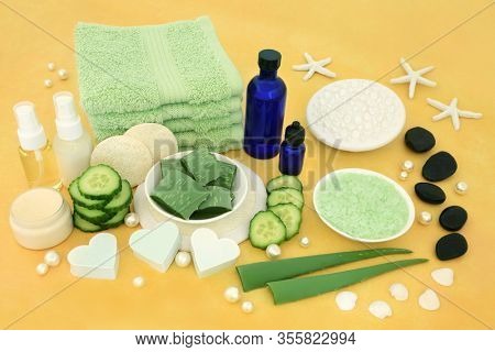 Natural spa vegan skincare beauty treatment with aloe vera & cucumber, spa stones, aromatherapy essential oils, ex foliation & cleansing products on yellow background.
