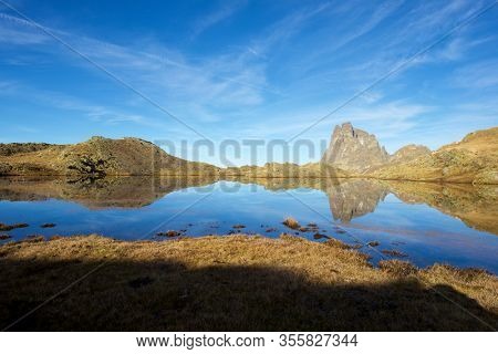 Midi Dossau Peak reflected in a lake. Ossau Valley, Pyrenees National Park, Pyrenees, France.