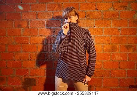 A Middle-aged Woman Poses Showing Clothes Near Red Brick Wall. An Inept Model In An Inept Shoot