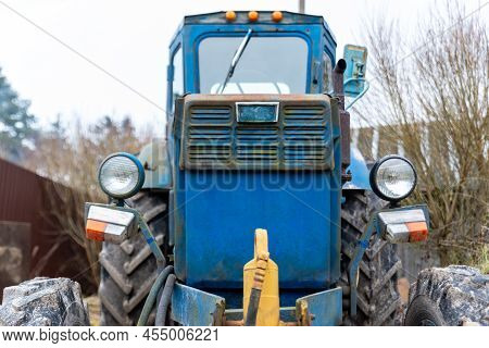 A Front Photo Of An Old Blue Tractor With Fence And Trees On Background