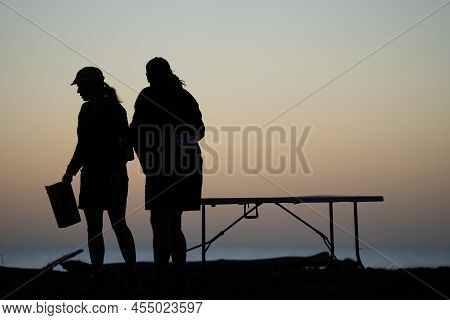 Whanganui New Zealand - April 9 2022; In Silhouette, Group Of Beach-goers After Sunset Enjoying A Be