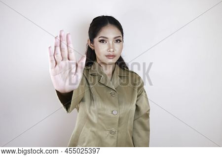 Young Asian Woman Wearing A Brown Uniform Shows Her Palm Or Stop Gesture