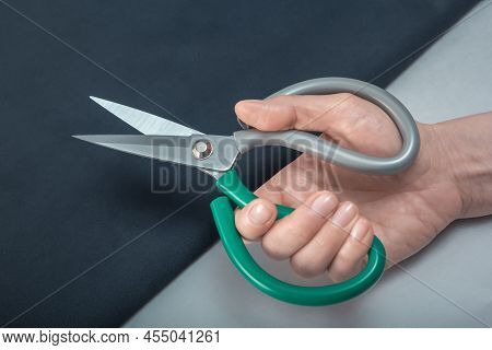 Open Scissors For Heavy Fabrics In A Female Hand Against The Background Of A Material. Close-up