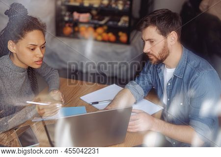 Hard-working Man And Woman Sturtupers Sitting At Table In Cafeteria And Discussing Project.
