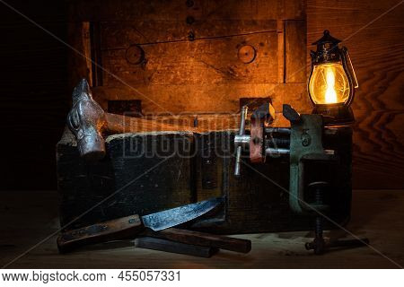 Still Life Of Tools. Old Knife, Hammer And Vise. Old Toolbox. Still Life In A Low Key. Lamp And Cand