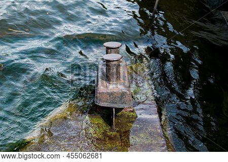 A Very Old, Rusty Iron Bollard On A Concrete Pier By The River. Pier At The Old River Station. Close