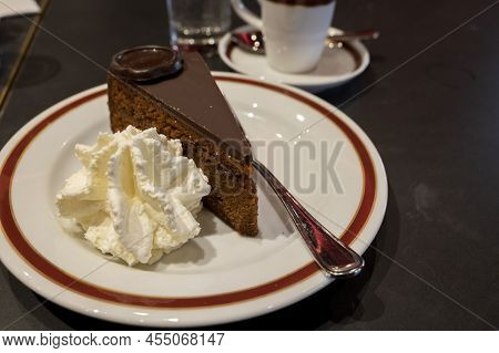 Piece Of Famous Sachertorte Chocolate Cake With Apricot Jam Of Austrian Origin Served With Whipped C