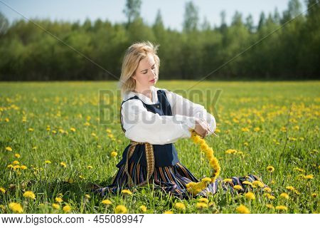 Young Woman In National Clothes Wearing Yellow Dandelion Wreath In Spring Field. Ligo