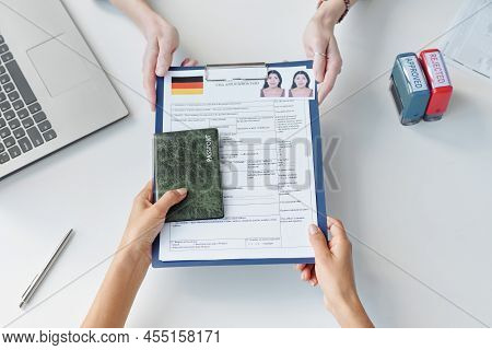 Top-down Shot Of Woman Applying For Travel Visa To Germany Giving Set Of Documents To Consular Offic