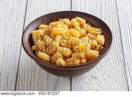 Uncooked Radiatori Pasta In Ceramic Bowl On White Wooden Background