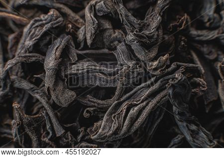 Black Loose Leaf Tea As A Background. Texture Of Dry Black Tea Leaves. Dark Background. Extreme Macr