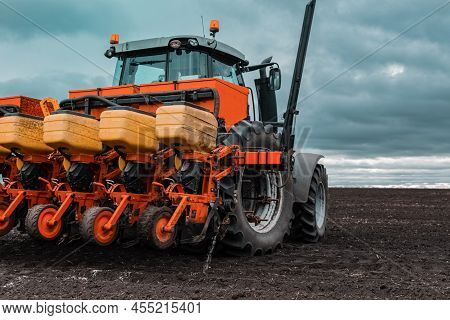 A Tractor With A Seed Drill Is Engaged In Planting Grain And Fertilizing. Seasonal Work In The Field